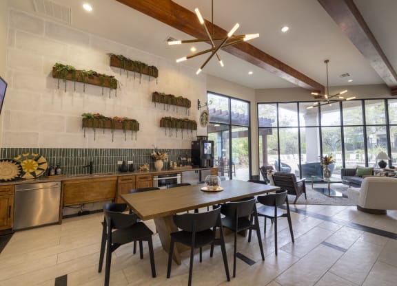 a dining room with a wooden table and chairs and a kitchen with large windows