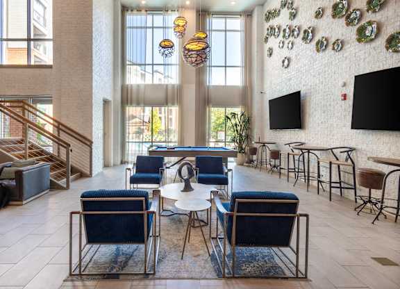 the lobby of a hotel with blue chairs and tables and large windows