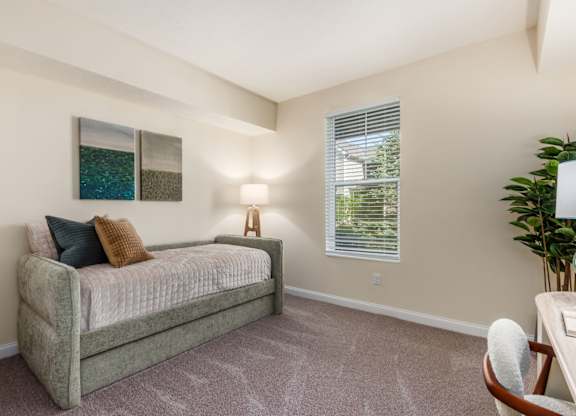 A bedroom with a bed, a chair, and a painting on the wall.