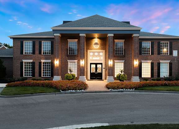 A large, well-lit house with a front yard and a driveway.