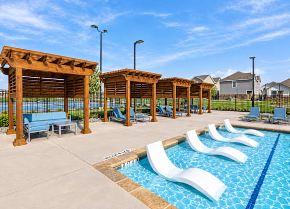 A pool area with sun loungers and a wooden pergola.