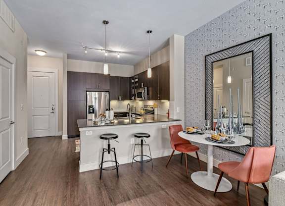 A kitchen with a bar stool and a dining table.