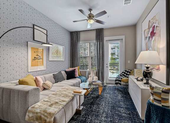A living room with a grey couch and a ceiling fan.