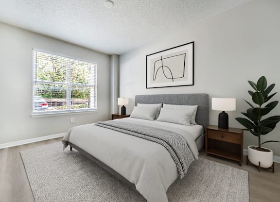 A bedroom with a large bed and a plant on the side table.