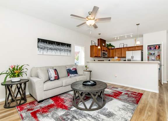 A living room with a couch, a coffee table, and a ceiling fan.