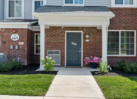 the front porch of a brick house with a green door