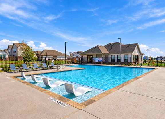 A pool with lounge chairs and a sign that says "Loveliness" in front of a row of houses.