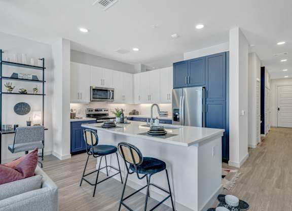 A kitchen with a white island and blue cabinets.