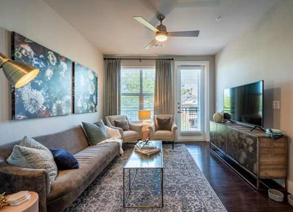 A living room with a brown couch, a glass coffee table, and a television on a wooden cabinet.