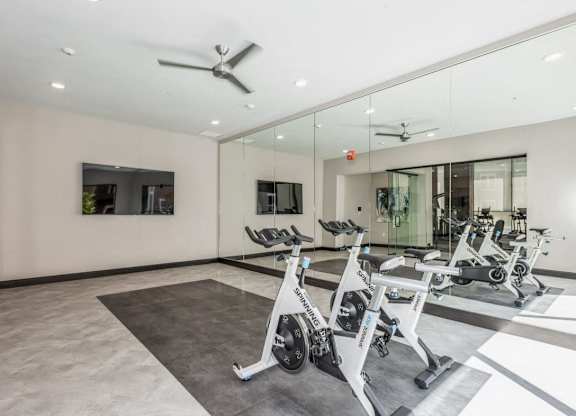 A gym with a mirrored wall and a fan.