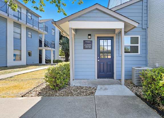 A small building with a sign that says "Valet Center" is in front of a row of apartment buildings.