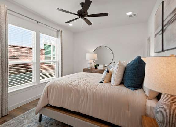 A bedroom with a bed, a ceiling fan, and a window with curtains.