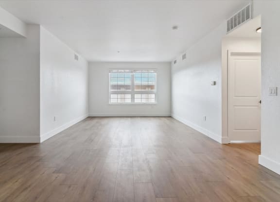 an empty living room with white walls and wood floors