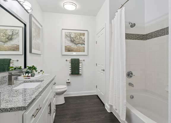 A bathroom with a white tub, sink, and toilet.