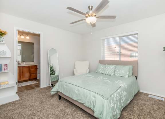 A bedroom with a bed, a ceiling fan, and a window with blinds.