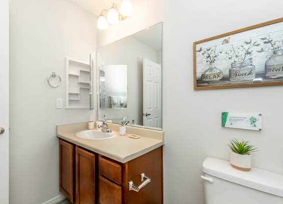 A bathroom with a white sink and brown cabinet.