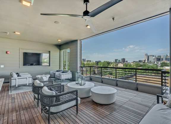A patio with a ceiling fan and a view of the city.