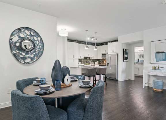 A modern dining room with a round table and grey chairs.