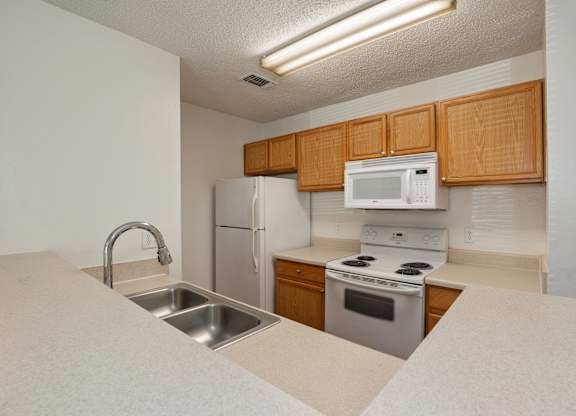 A kitchen with white appliances and wooden cabinets.