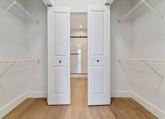an empty closet with white doors and white walls and wood floors