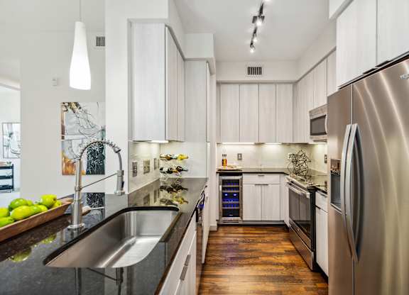 A modern kitchen with a stainless steel refrigerator and wooden floors.