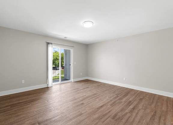 a living room with wood floors and a door to a balcony
