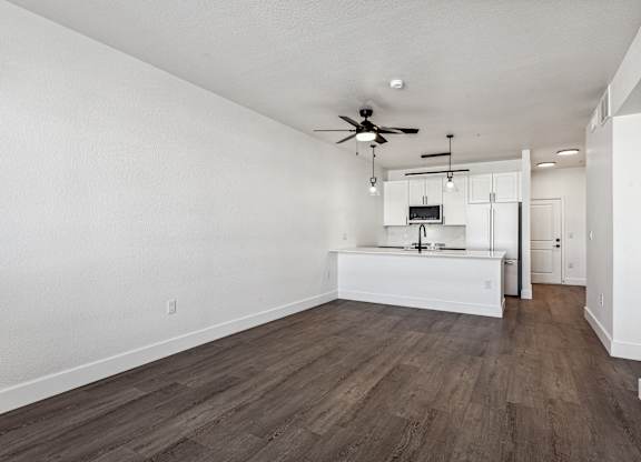 A room with a ceiling fan and a kitchenette.