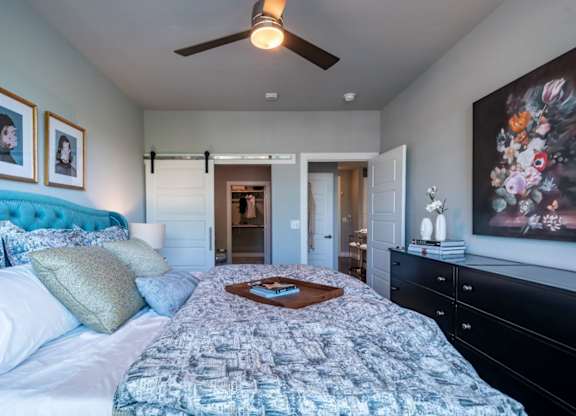 A bedroom with a patterned bedspread and a ceiling fan.