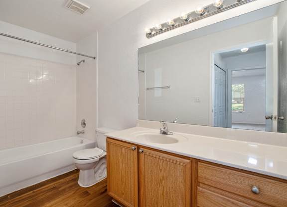 A white bathroom with wooden cabinets and a white toilet.