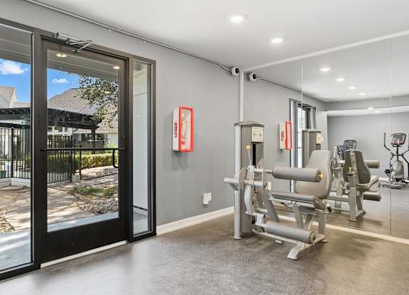 A gym with a view of a courtyard through a glass door.