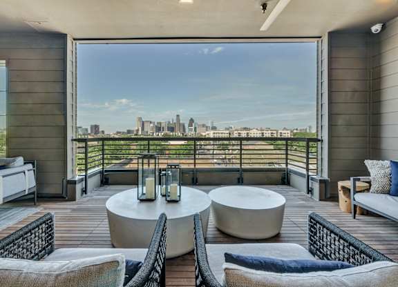 A balcony with a table and chairs overlooking a city skyline.