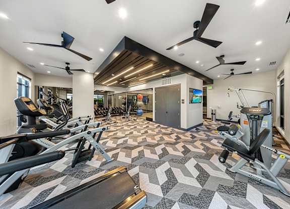 A spacious gym with a variety of equipment and a patterned floor.