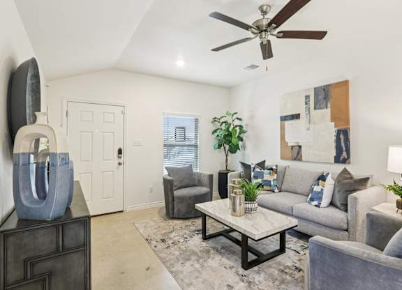 A living room with a grey couch, a coffee table, and a ceiling fan.