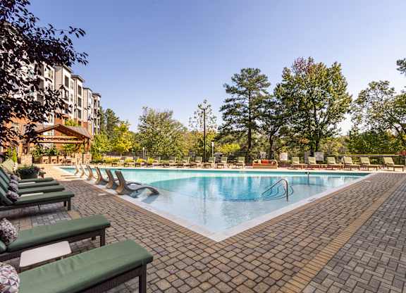 a swimming pool with chairs and a building in the background