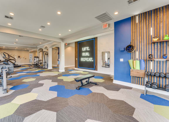 a gym with weights and cardio machines and a chalkboard on the wall