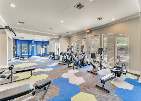 a gym with cardio machines and weights on the floor at the community center