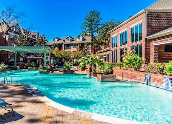 A large swimming pool surrounded by lounge chairs and trees.
