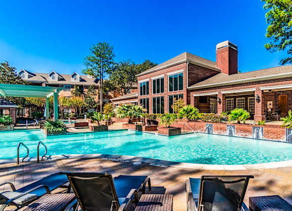 A pool with chairs and a building in the background.