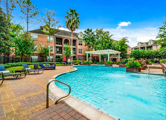A swimming pool surrounded by a brick patio and a building in the background.