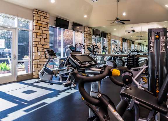 A gym with a variety of exercise equipment including treadmills, stationary bikes, and weight machines.