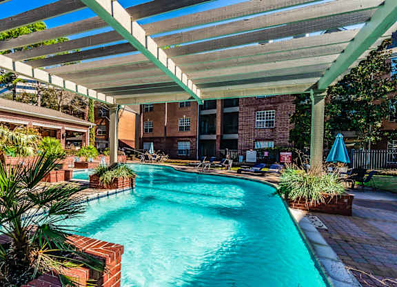 A pool under a white canopy with a building in the background.