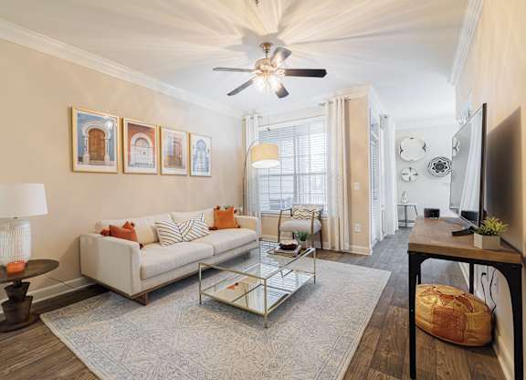 A living room with a white couch, a coffee table, and a ceiling fan.