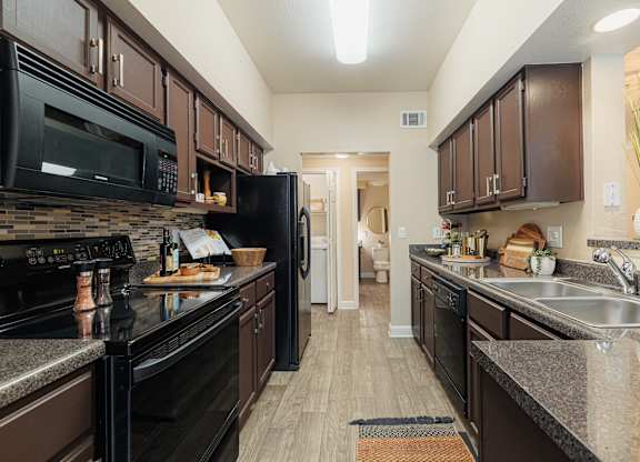 A kitchen with black appliances and brown cabinets.