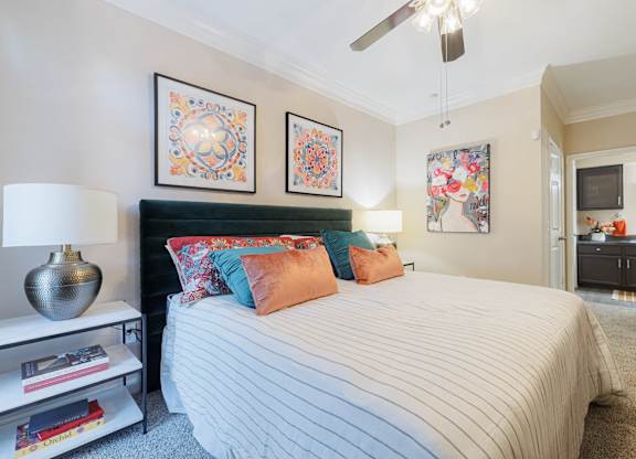 A bedroom with a bed, a nightstand with a lamp, and two framed pictures on the wall.