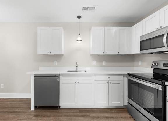an empty kitchen with white cabinets and stainless steel appliances