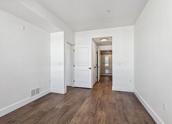A long hallway with wood floors and white walls.