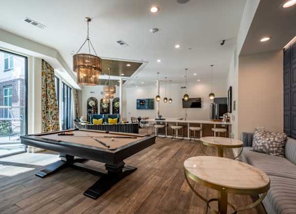 A billiard table is in the middle of a room with a couch and a table.