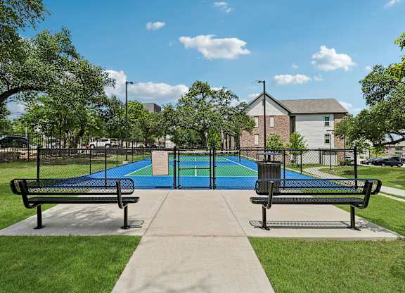 A playground with a blue surface and two benches.