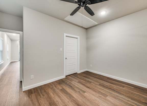 A room with a ceiling fan and wooden flooring.