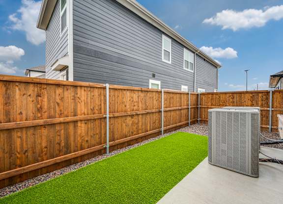 A backyard with a wooden fence and a green lawn.